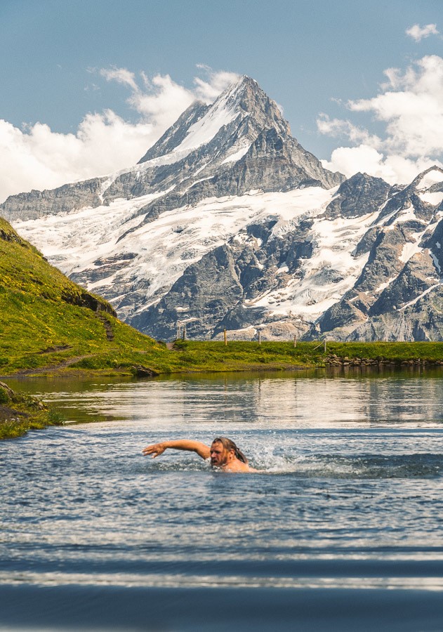山を背景に湖で泳ぐ男性。