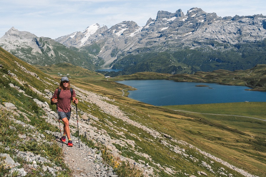 湖を背景に急な丘をハイキングする男性。