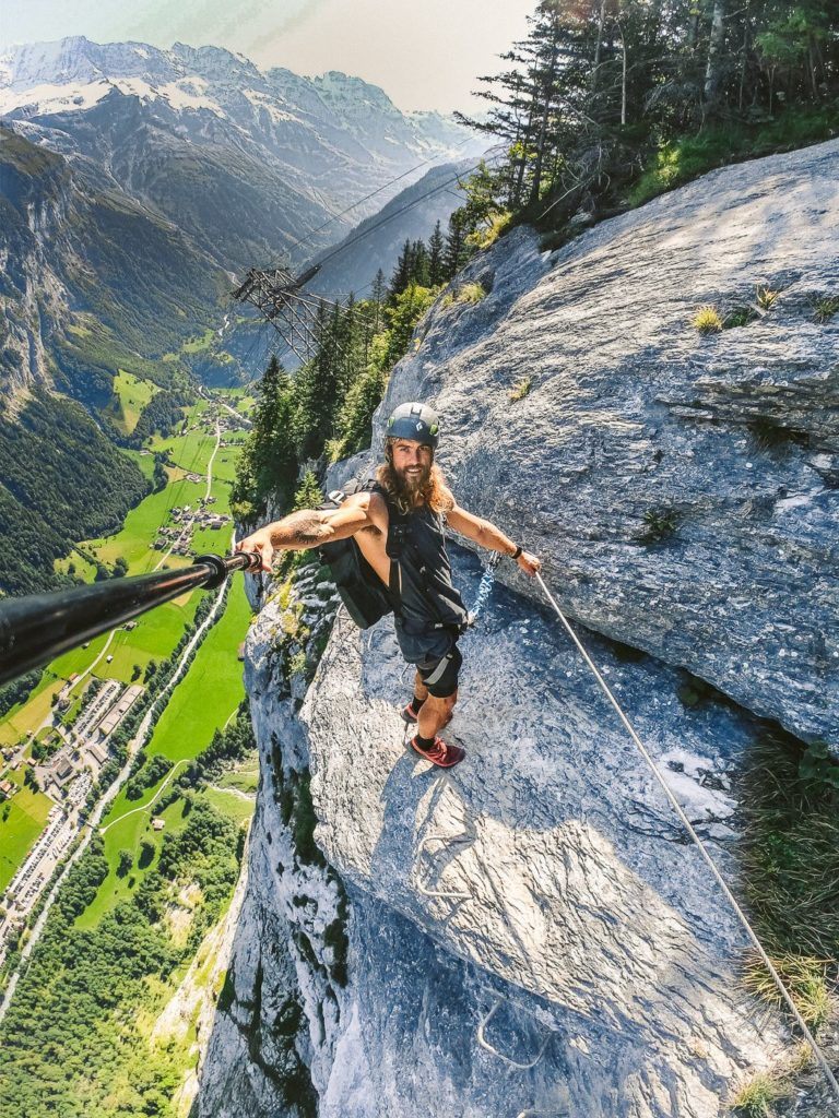 山の頂上でロープにぶら下がっている男性。