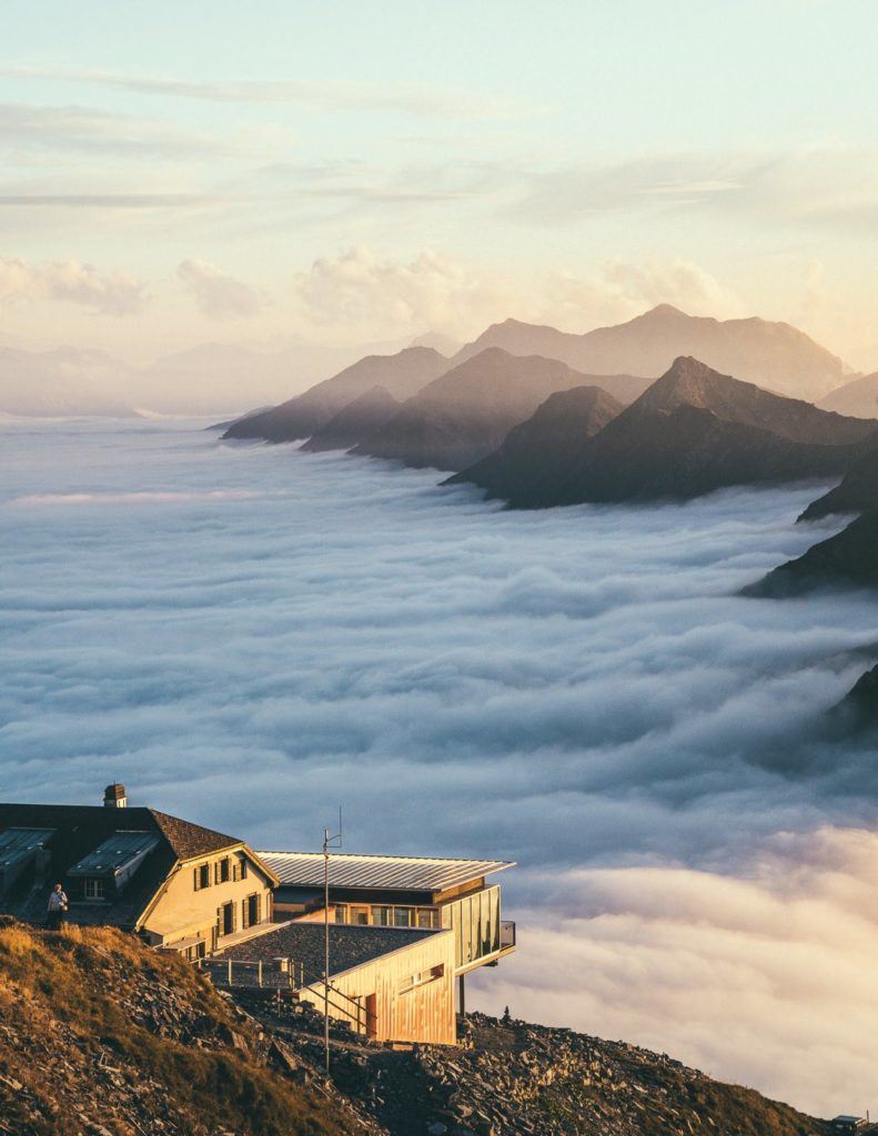 雲に覆われた山の頂上に建つ家。