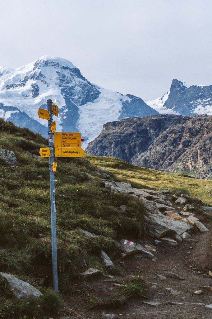 山を背景に岩だらけの小道にある黄色の標識。